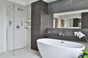 bagno con vasca bianca e specchio di Hotel Lantier Bytom - Katowice - Chorzów a Bytom