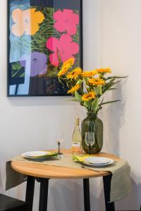 a table with a vase of flowers and a painting at Kwiatowa Apartments Poznań City Center by Renters in Poznań