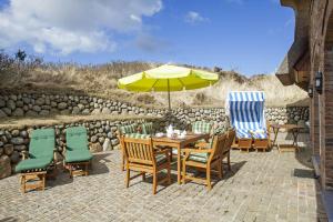 un patio avec une table, des chaises et un parasol dans l'établissement Senenskiin, à List auf Sylt