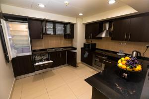 uma cozinha com armários pretos e uma taça de fruta no balcão em Imperial Suites Hotel em Doha