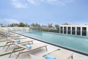 a large swimming pool with lounge chairs on a building at JonoX Phuket Karon Hotel in Karon Beach