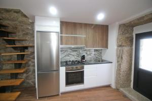a kitchen with a stainless steel refrigerator and wooden cabinets at Casa do Mestre by Gerês Casas in Geres