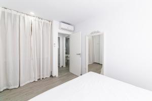 a white bedroom with white curtains and a bed at Apartamentos “Mar de Coral” Aguadulce in Aguadulce