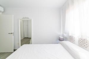 a white bedroom with a bed and a window at Apartamentos “Mar de Coral” Aguadulce in Aguadulce