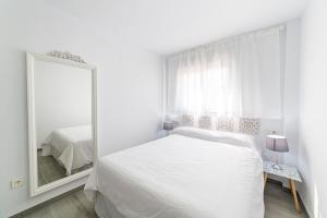 Dormitorio blanco con espejo y cama en Apartamentos “Mar de Coral” Aguadulce, en Aguadulce