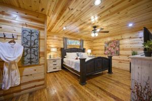 a log cabin bedroom with a bed and a ceiling fan at Shear Pleasure in Broken Bow