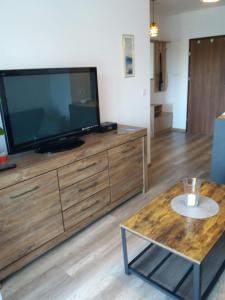 een woonkamer met een grote televisie op een houten dressoir bij Apartament Magda in Kołobrzeg