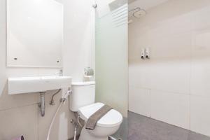 a white bathroom with a toilet and a sink at RedDoorz Plus @ Point Phila Cihampelas in Bandung