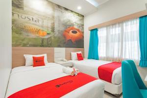 two beds in a room with a painting on the wall at RedDoorz Plus @ Point Phila Cihampelas in Bandung