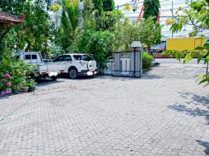 two trucks parked next to a gate in a driveway at RedDoorz near Politeknik Perkeretaapian Indonesia Madiun in Madiun