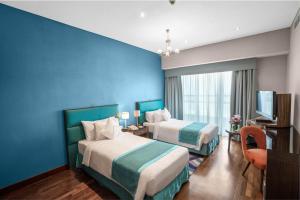 a hotel room with two beds and a blue wall at City Premiere Hotel Apartments - Dubai in Dubai