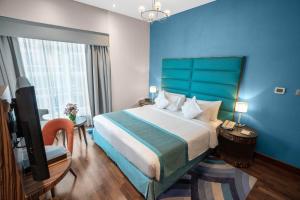 a bedroom with a large bed and a blue wall at City Premiere Hotel Apartments - Dubai in Dubai