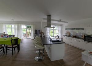 a kitchen with white cabinets and a green table at Haus Rosengarten- Ruhige Ferienwohnungen im Grünen in Sehlen