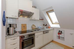キュールングスボルンにあるHaus-Rolandseck-Wohnung-11-416の白いキャビネット、シンク、窓付きのキッチン