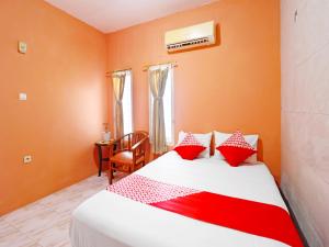 1 dormitorio con 1 cama con almohadas rojas y blancas en OYO 91408 Kas Residence Syariah en Jambi