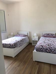 two beds in a bedroom with wooden floors at Le maioliche allo Stagnone kite in Marsala