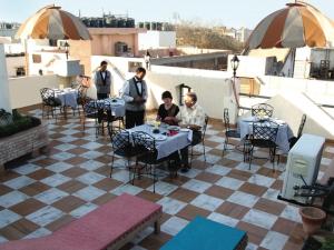 un groupe de personnes assises à des tables sur un patio dans l'établissement Hotel Sunstar Grand, à New Delhi