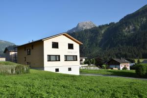 ein Haus auf einem Hügel mit Bergen im Hintergrund in der Unterkunft BergZeit Schoppernau in Schoppernau