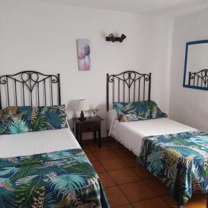 1 dormitorio con 2 camas y mesa con lámpara en Casa Los Mangos, en Tijarafe