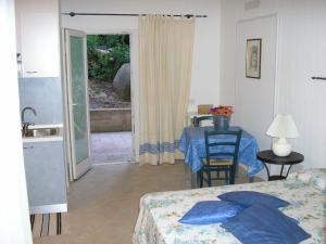 a bedroom with a bed and a table and a kitchen at Appartamenti Il Giardino in Porto Rotondo