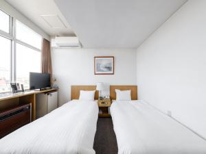 um quarto de hotel com duas camas e uma televisão em Tabist THE GREEN ASAHIKAWA em Asahikawa