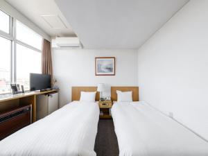 een hotelkamer met 2 bedden en een televisie bij Tabist THE GREEN ASAHIKAWA in Asahikawa