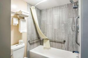 a bathroom with a white tub and a toilet at Rodeway Inn North Chesterfield-Richmond in Richmond