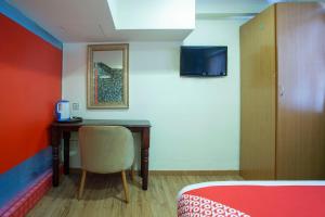 a room with a desk with a chair and a bed at Super OYO Capital O 90125 Hotel Grand Orchard in Kuala Lumpur