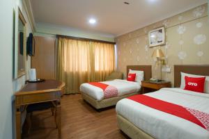 a hotel room with two beds and a desk at Super OYO Capital O 90125 Hotel Grand Orchard in Kuala Lumpur