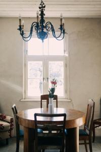 een eetkamer met een houten tafel en een kroonluchter bij Kalnciema kvartāla Kuldīgas rezidence in Kuldīga