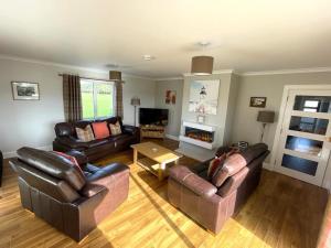 a living room with leather furniture and a fireplace at Tigh Grianach in Connel