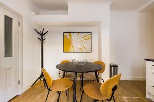 une salle à manger avec une table noire et des chaises jaunes dans l'établissement The Fulham Bolthole - Beckoning 2BDR Flat with Garden, à Londres