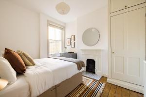 Dormitorio blanco con cama y chimenea en The Fulham Bolthole - Beckoning 2BDR Flat with Garden, en Londres
