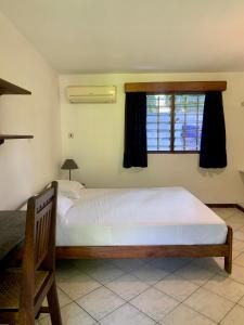 Un dormitorio con una gran cama blanca y una ventana en Baobab Village Studio, en Dar es Salaam