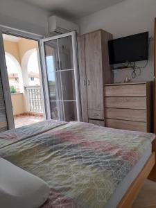 um quarto com uma cama, uma televisão e uma cómoda em Apartmani Slavko em Fažana
