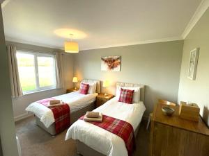 a bedroom with two beds and a window at Tigh Grianach in Connel