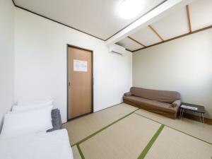 Tabist Diversity Hotel Sin Tokiwa Asahikawa في اساهيكاو: غرفه فيها سرير واريكه