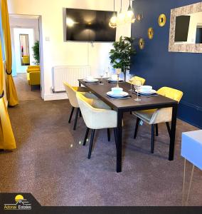 a dining room with a table with yellow chairs at Priorswood House in Taunton