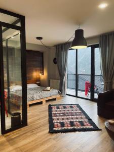 a bedroom with a bed and a large glass window at Kazbegi Stylish Apartment in Stepantsminda