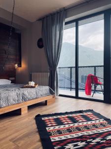 a bedroom with a bed and a large window at Kazbegi Stylish Apartment in Kazbegi
