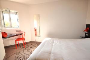 1 dormitorio con cama, escritorio y espejo en The Originals Access, Hôtel Limoges Nord en Limoges