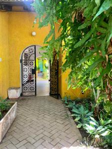 an entrance to a yellow building with an open gate at Baobab Village Studio in Dar es Salaam