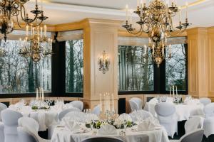 a room with white tables and chairs and chandeliers at Hotel Forsthaus Nürnberg Fürth in Fürth