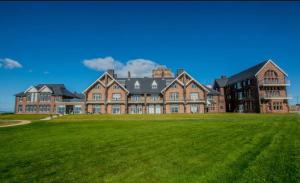 a large brick building with a large grass field at The Sandpiper's Pearl in Nottage