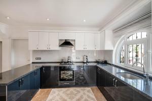 a kitchen with black and white cabinets and a sink at Sessiz,Sakin, huzurlu jakuzi ve saunalı deniz,doğa manzaralı müstakil villa in Fethiye