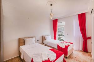 two beds in a room with red curtains and a window at Sessiz,Sakin, huzurlu jakuzi ve saunalı deniz,doğa manzaralı müstakil villa in Fethiye