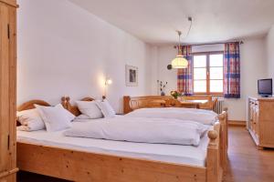 Un dormitorio con una gran cama de madera con sábanas blancas. en Zentrum für Umwelt und Kultur - Gästehaus und Jugendbildungseinrichtung im Maierhof en Benediktbeuern