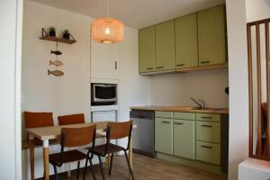 una cocina con armarios verdes, mesa y sillas en HHVDK aan zee, en Oostduinkerke