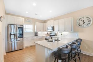 a kitchen with white cabinets and a large clock on the wall at Dark Side Of The Dune home in Port Bolivar