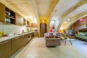 cocina y sala de estar con sofá y mesa en The Valley Holiday Home en Kerċem